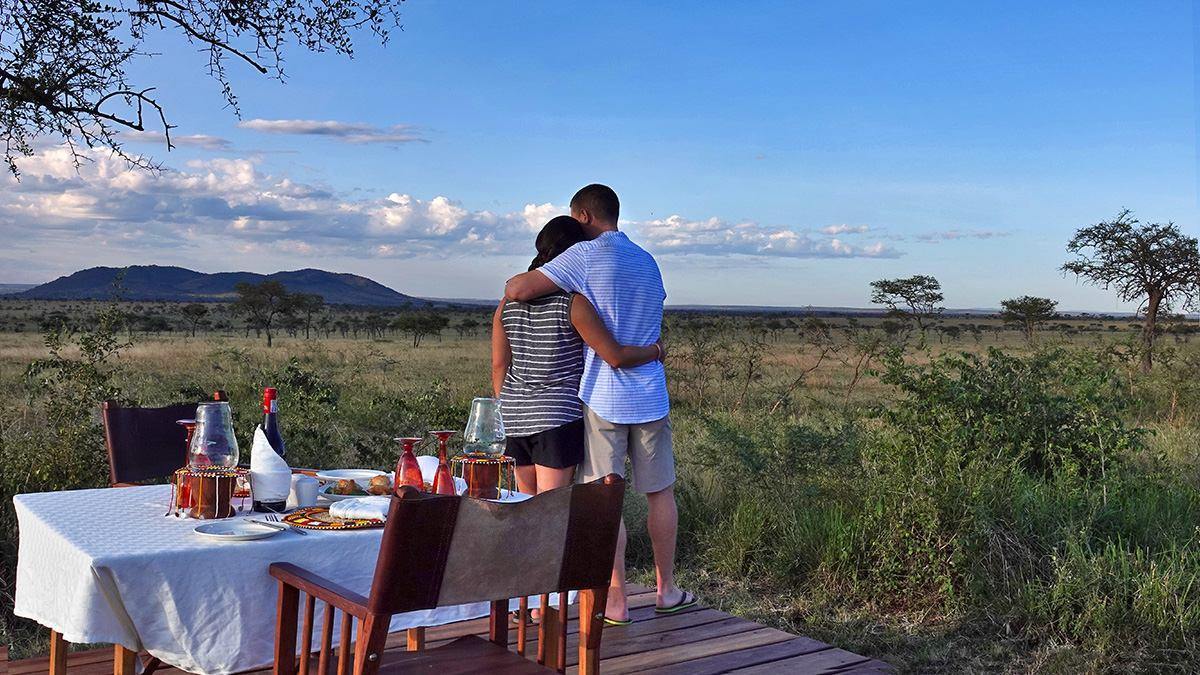 A couple at a candlelit bush dinner table on the savannah